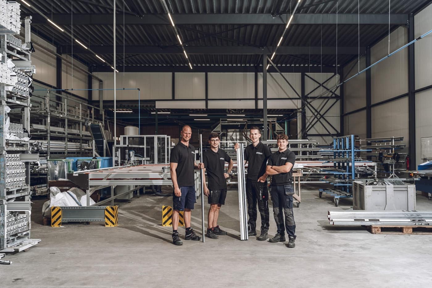 Vier medewerkers van Skodora staan met kozijnprofielen in de productiehal in Heerenveen