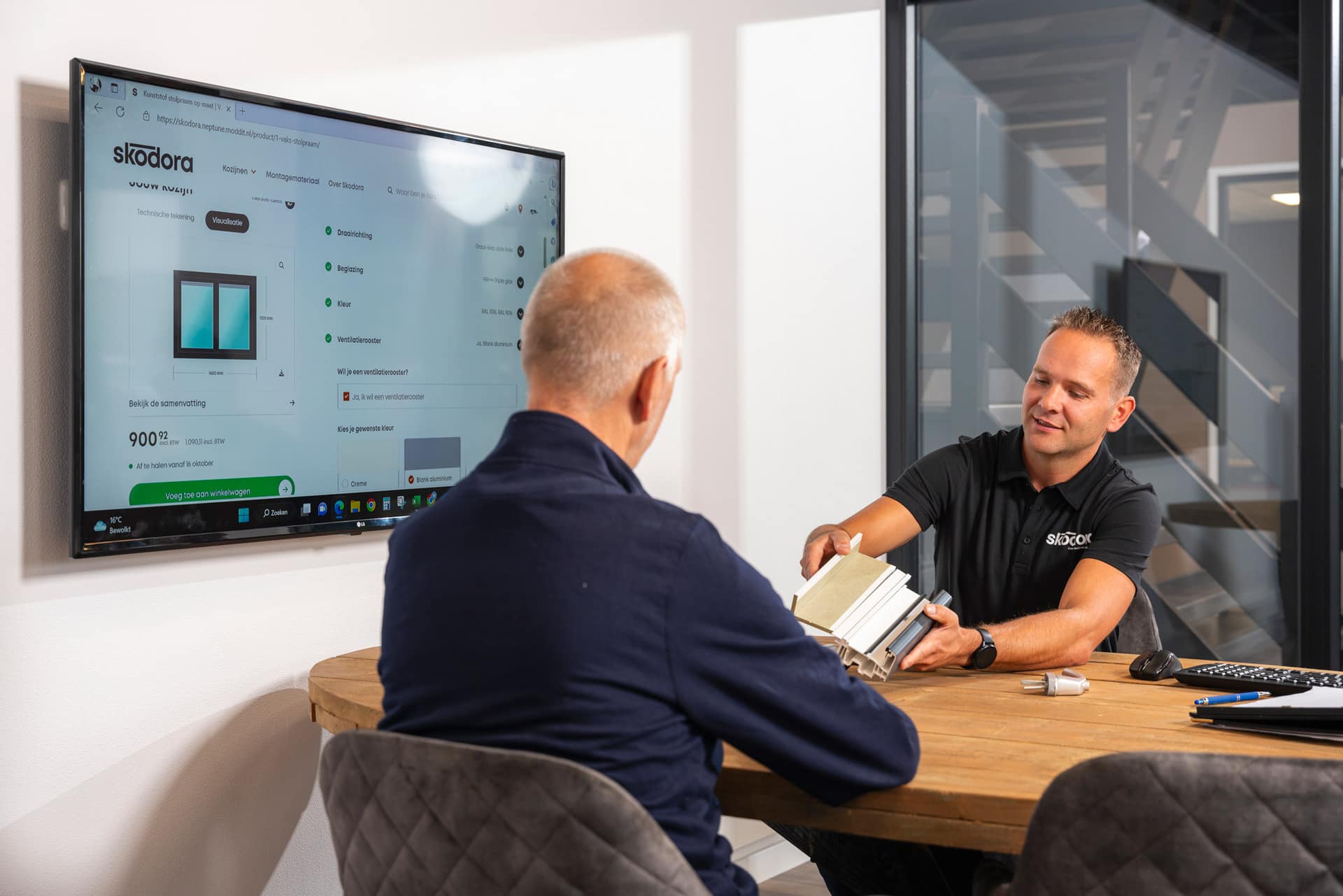 Een medewerker van Skodora laat een klant een kozijnprofiel zien, met de online configurator op een scherm